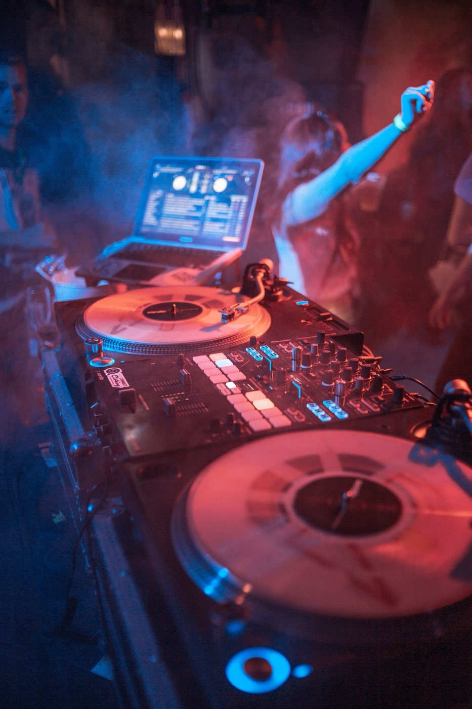 DJ booth with turntables and mixer under red and blue lights